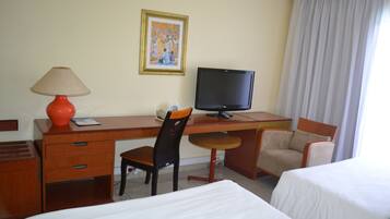 Una habitación de hotel con escritorio, dos sillas, cama y televisor.