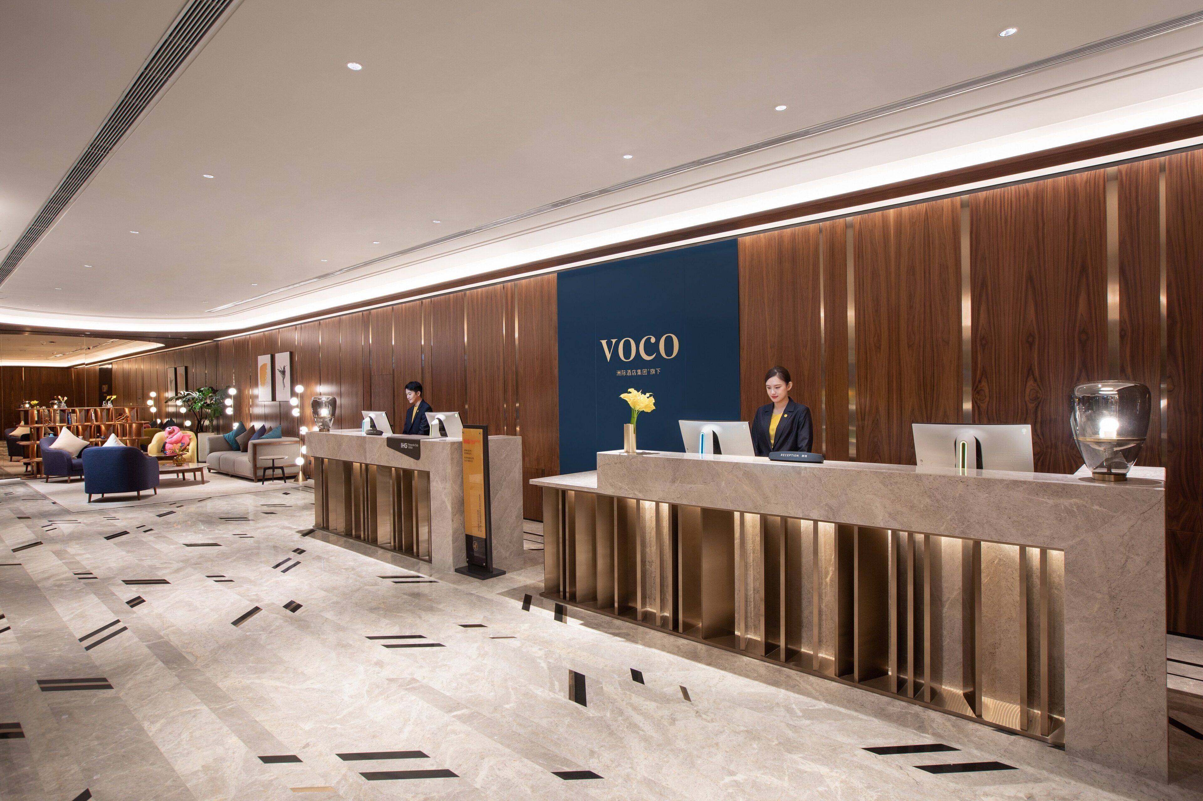 A modern reception area with a wooden panel wall and a blue sign reading "VOCO".