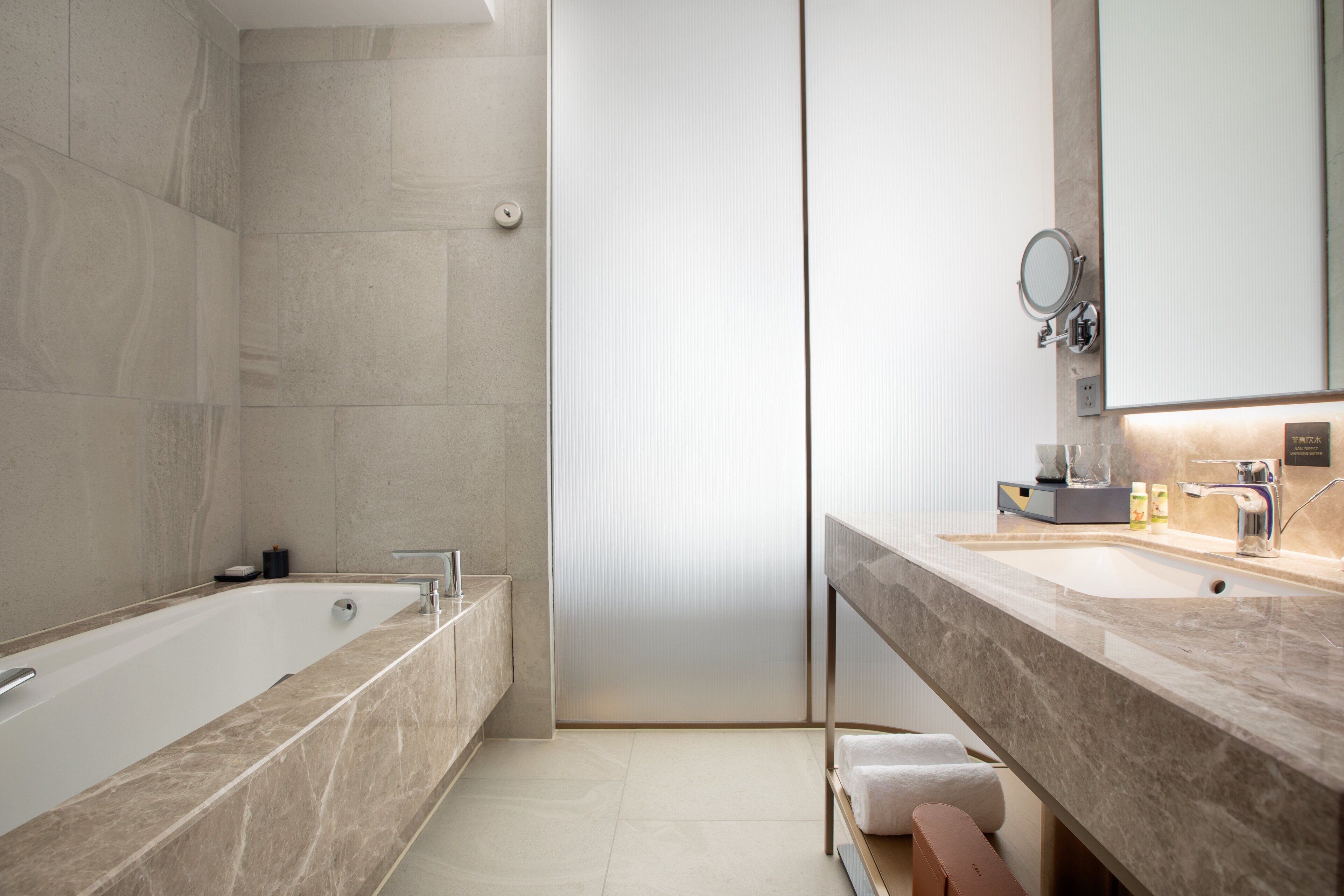 Un baño moderno con una bañera independiente, un tocador con espejo y un perchero para toallas.