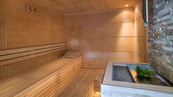 A sauna with wooden benches and a stone wall.
