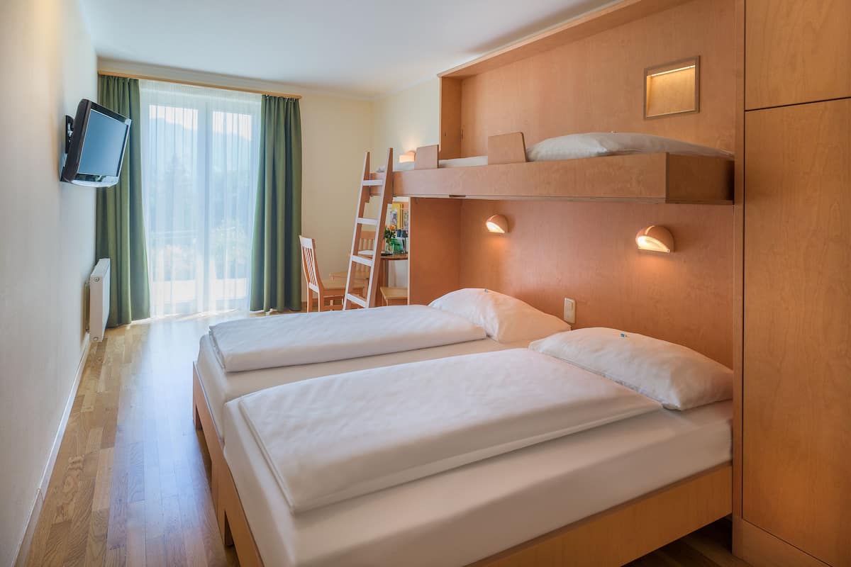 A hotel room with two beds, a TV mounted on the wall, and a wooden headboard.