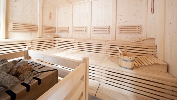 A traditional Japanese onsen with wooden benches and a stone basin. - JUFA Hotel Altaussee (Altaussee)