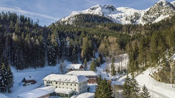 A snow-covered mountain landscape with a building featuring multiple windows and a snow-covered roof.