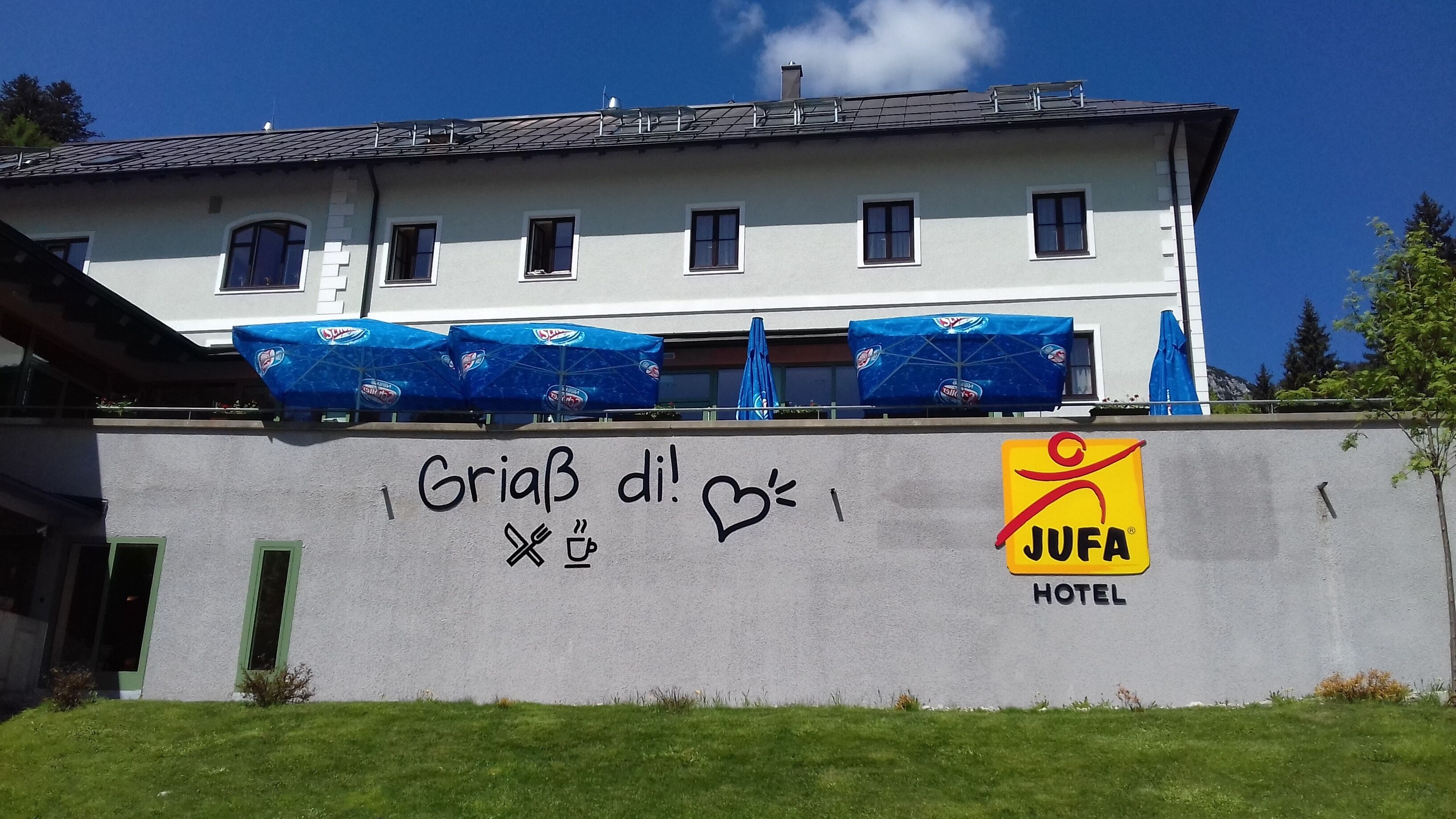 Un hôtel avec une façade en béton, un logo bien visible et un message écrit en graffiti.