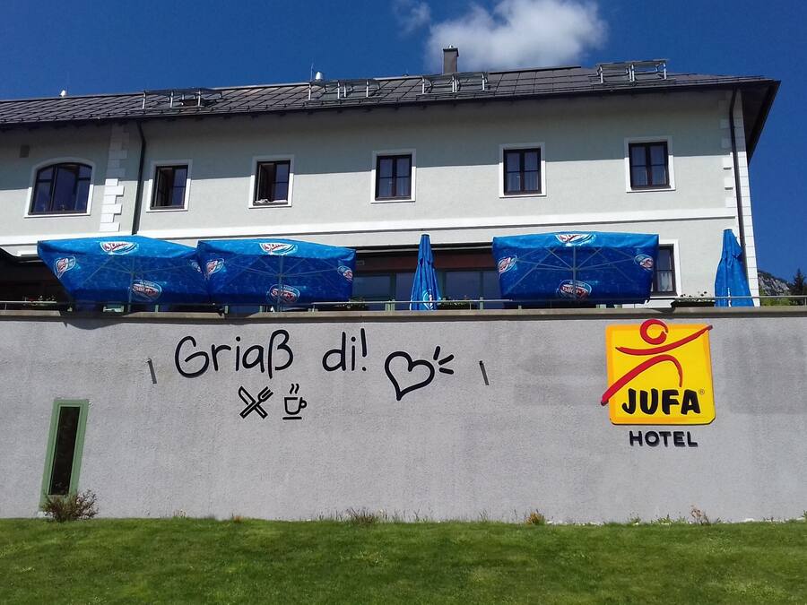 Un hôtel avec une façade en béton, un logo bien visible et un message écrit en graffiti.