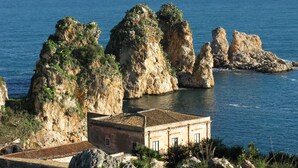 Un edificio costero con techo de tejas, ubicado cerca de acantilados rocosos y el mar.