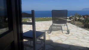 Una silla y una mesa en un patio de piedra con vista al mar.