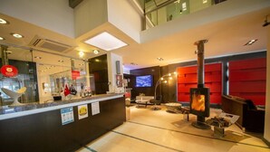 Un vestíbulo moderno con una mesa de recepción, una chimenea y una pantalla de televisión.