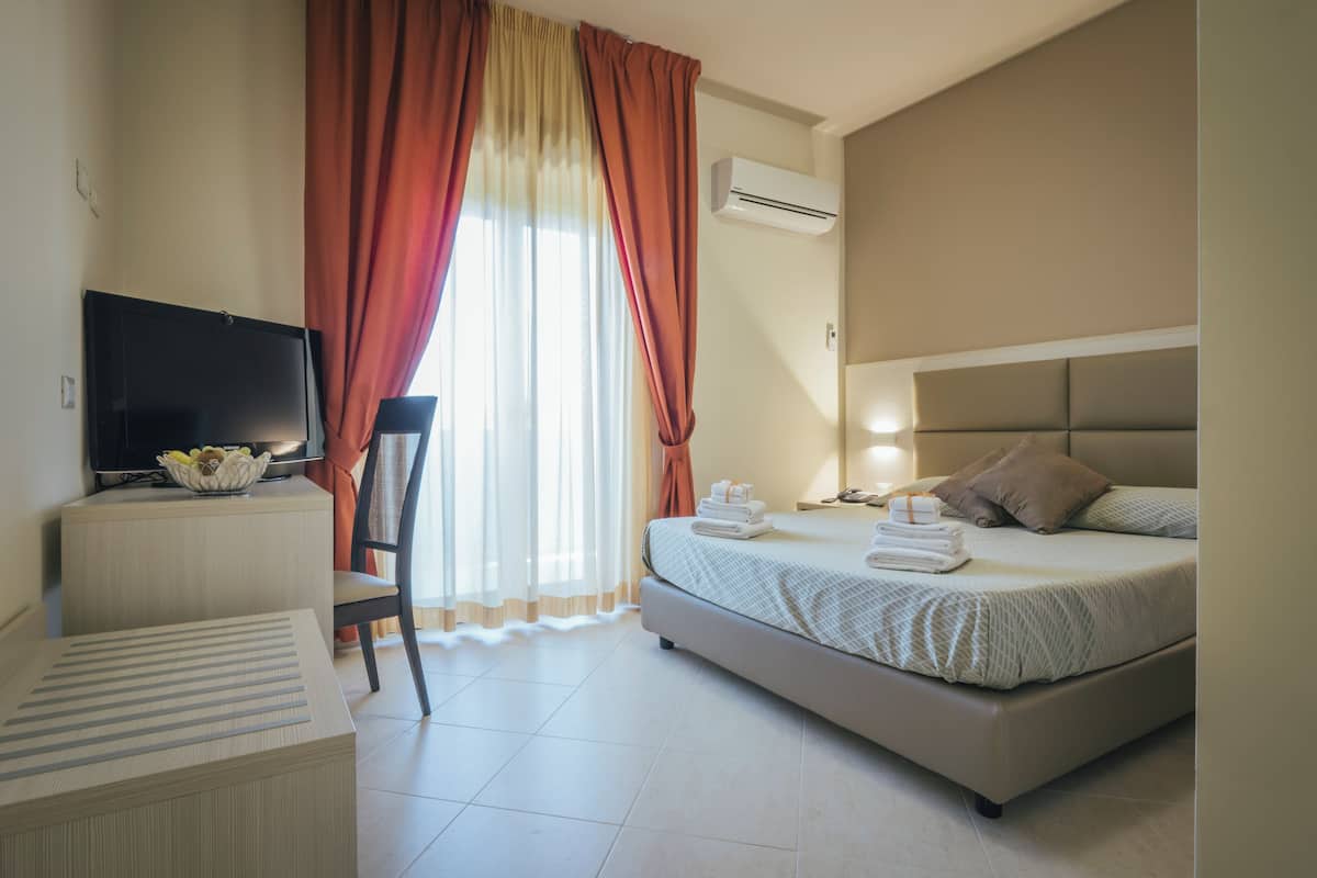 A hotel room with a bed, a TV, a desk, and a chair.