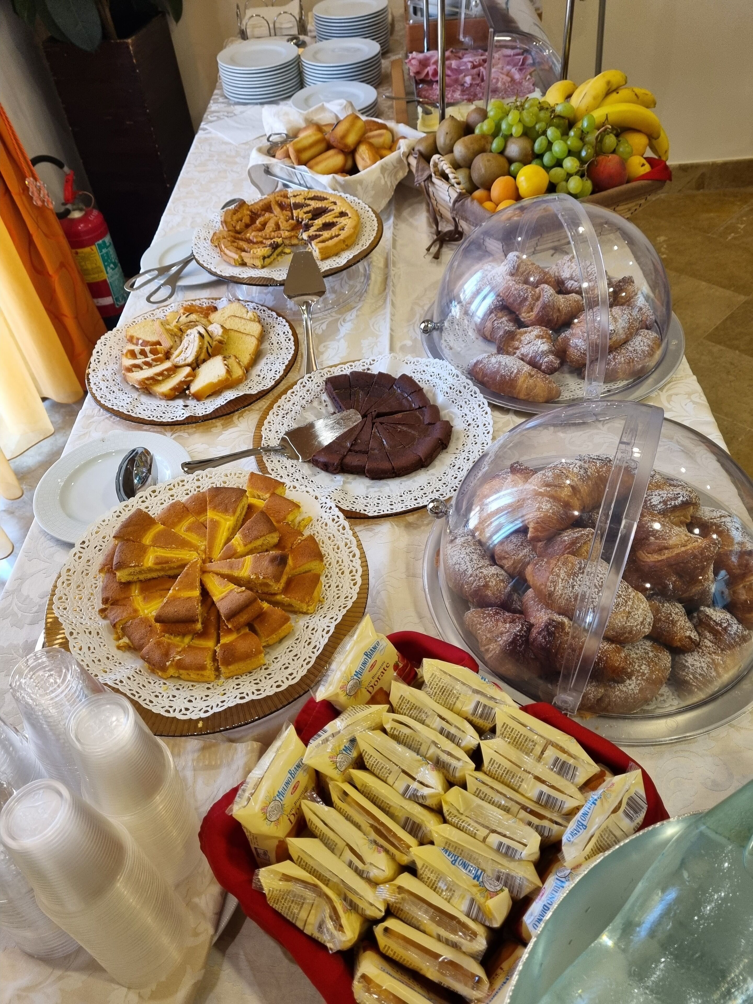 Une table de buffet proposant divers plats, notamment des tartes, des pâtisseries et du pain.