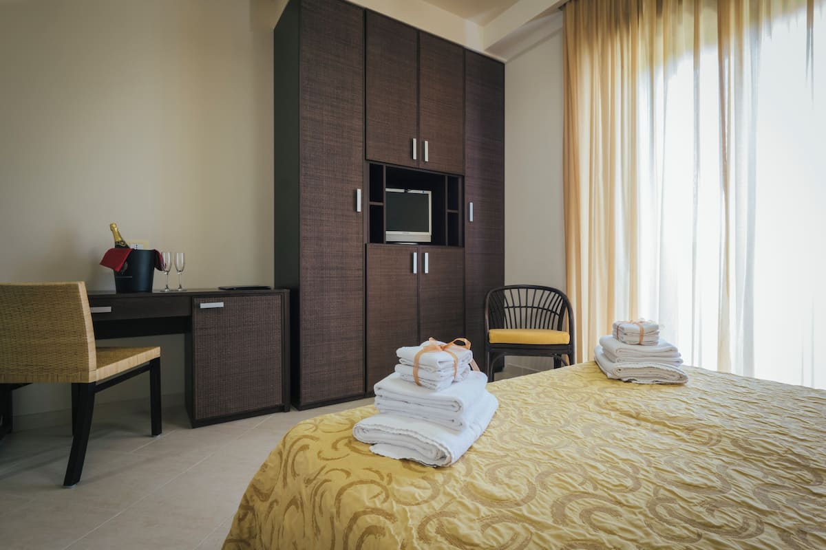 A hotel room with a bed, a desk, a television, and a wardrobe.