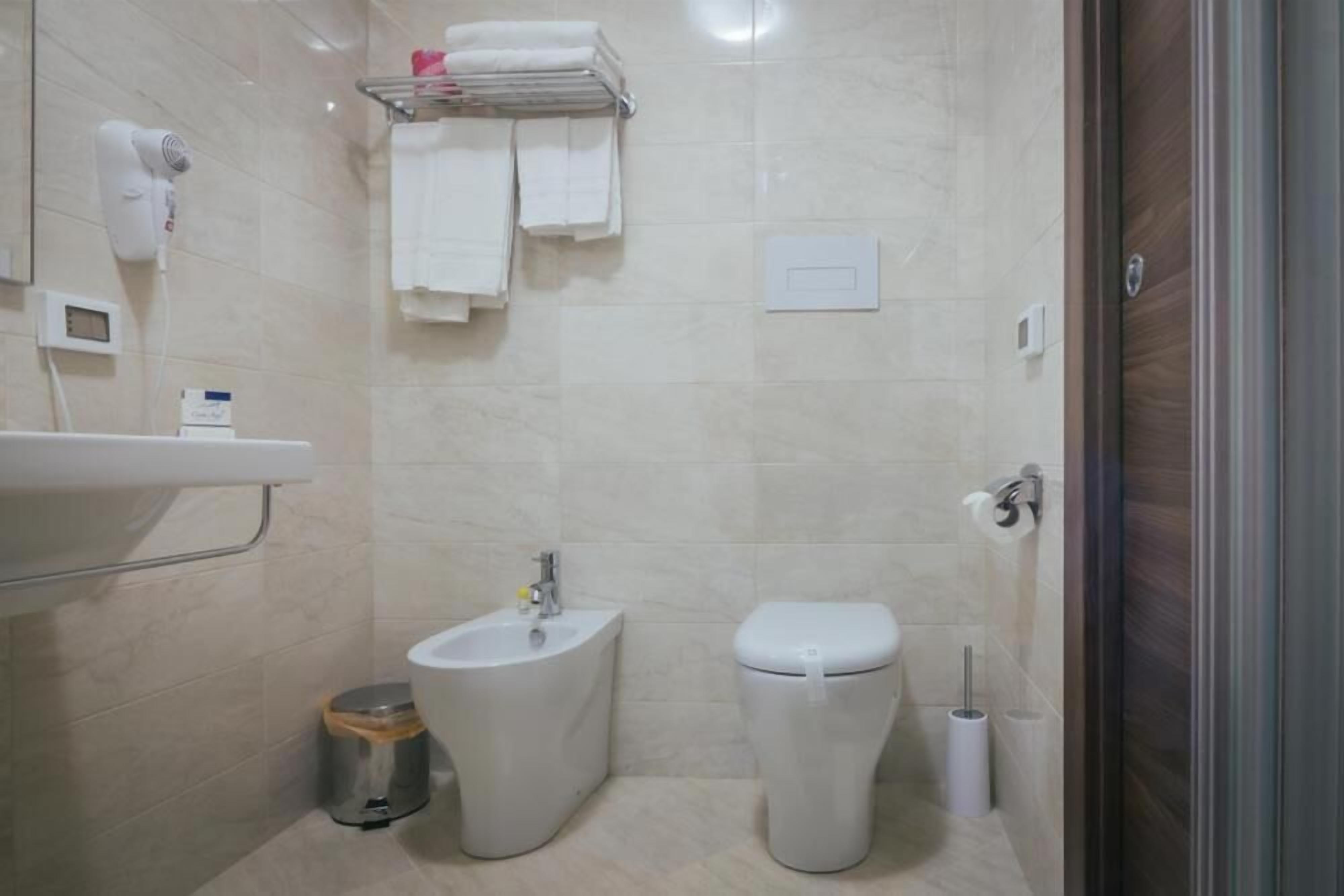 Ein modernes Badezimmer mit Waschbecken, Bidet, Toilette und einem Handtuchhalter mit Handtüchern.