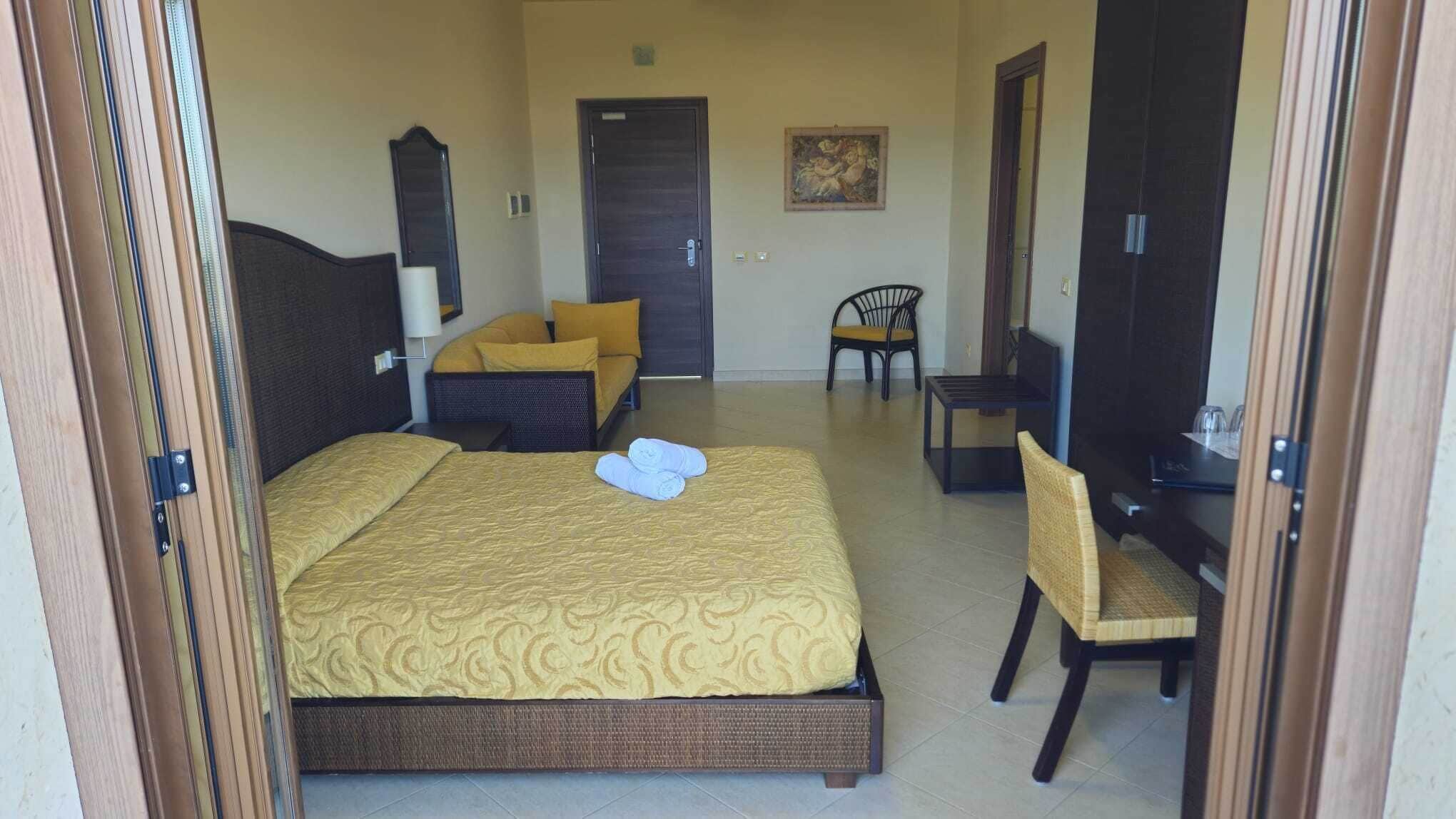 Een hotelkamer met een bed, een stoel, een bureau en een televisie.