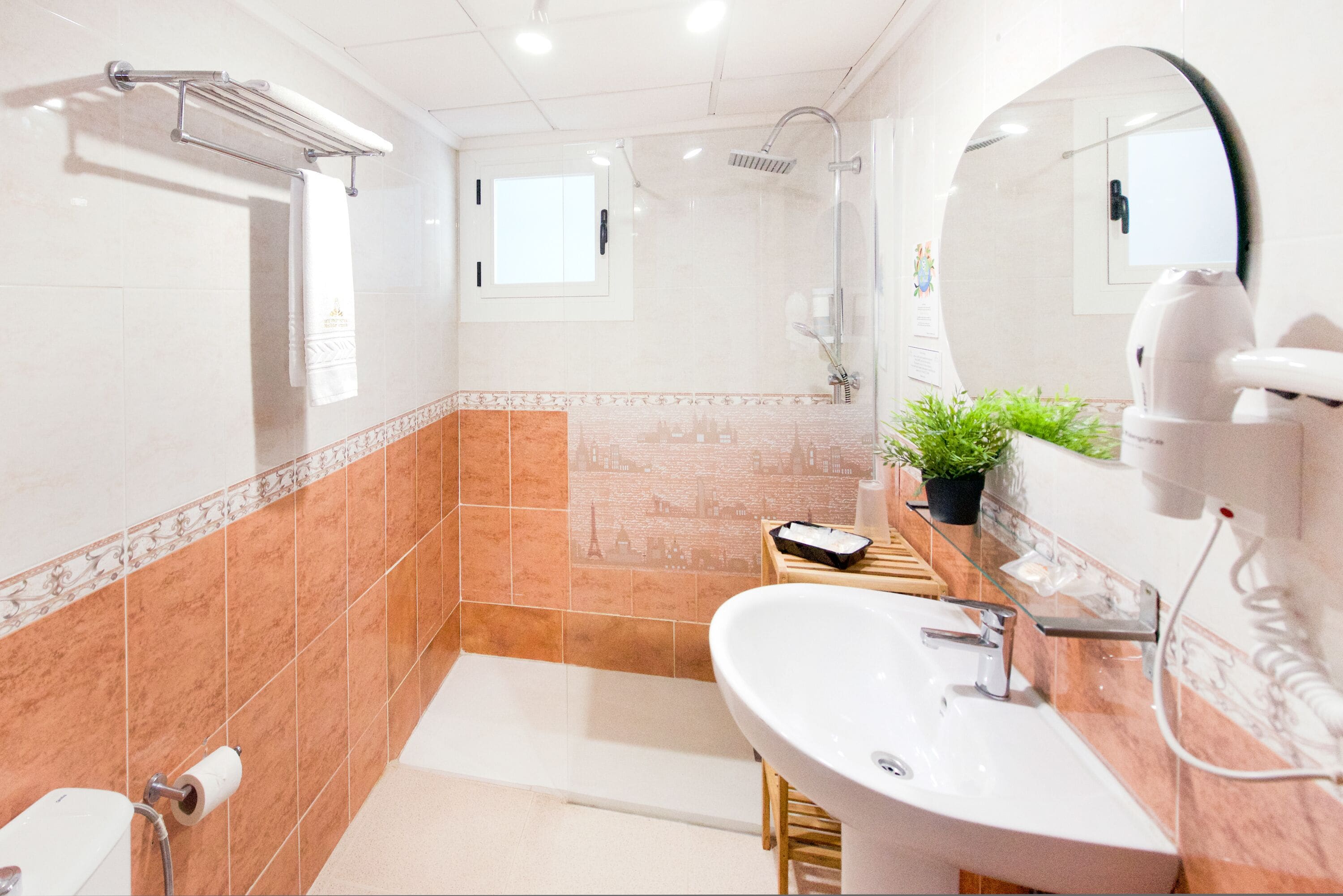 Un baño moderno con un espejo grande, un lavamanos, una ducha y un inodoro.