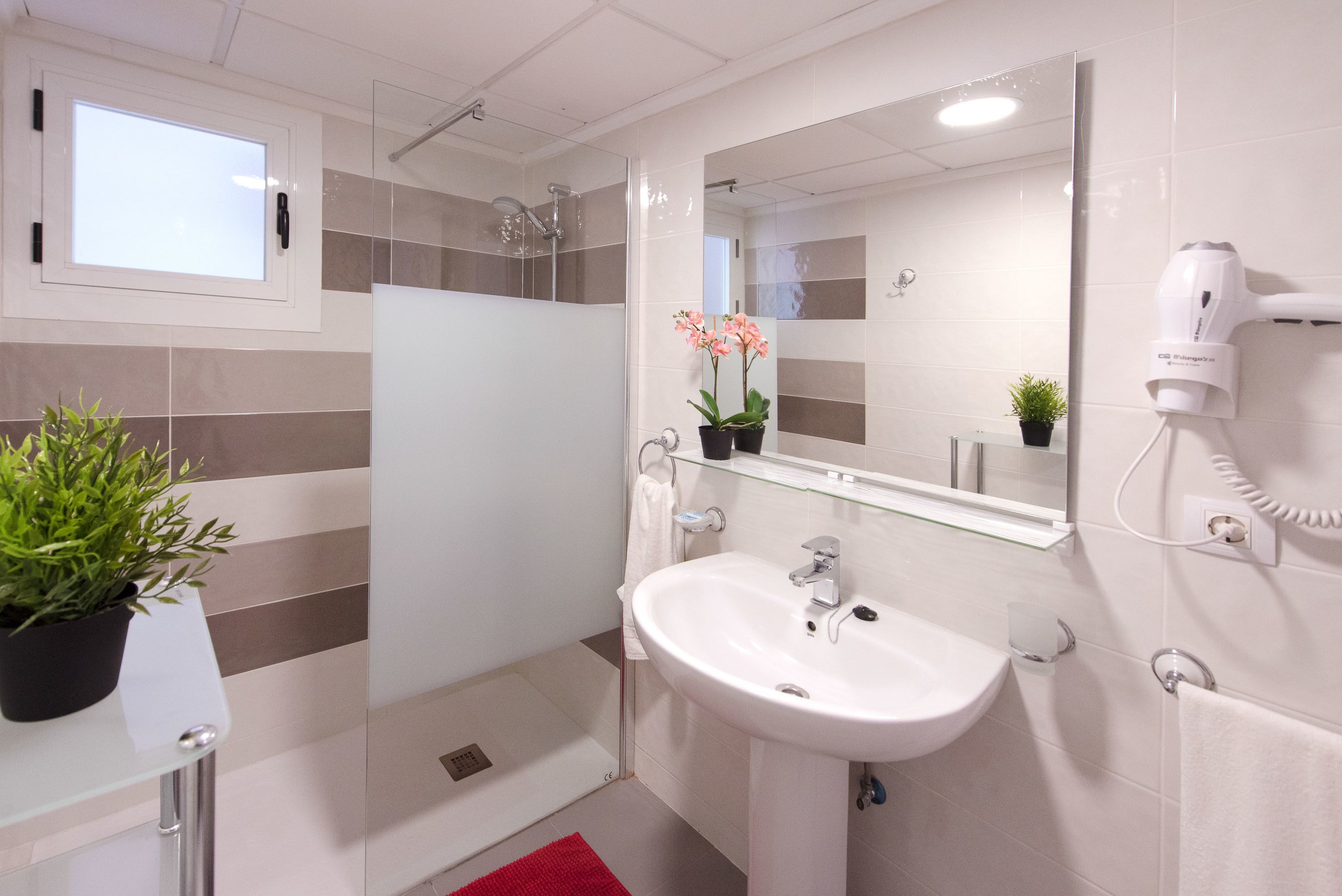 Un baño moderno con cabina de ducha de vidrio, un lavabo blanco y un espejo encima.