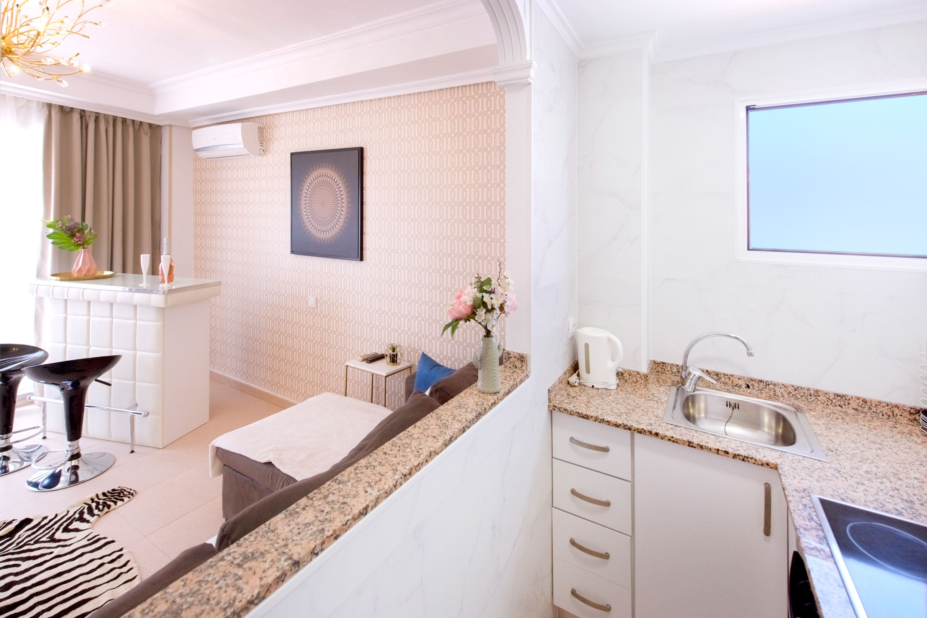 A modern hotel room with a kitchenette, a dining area, and a bed.