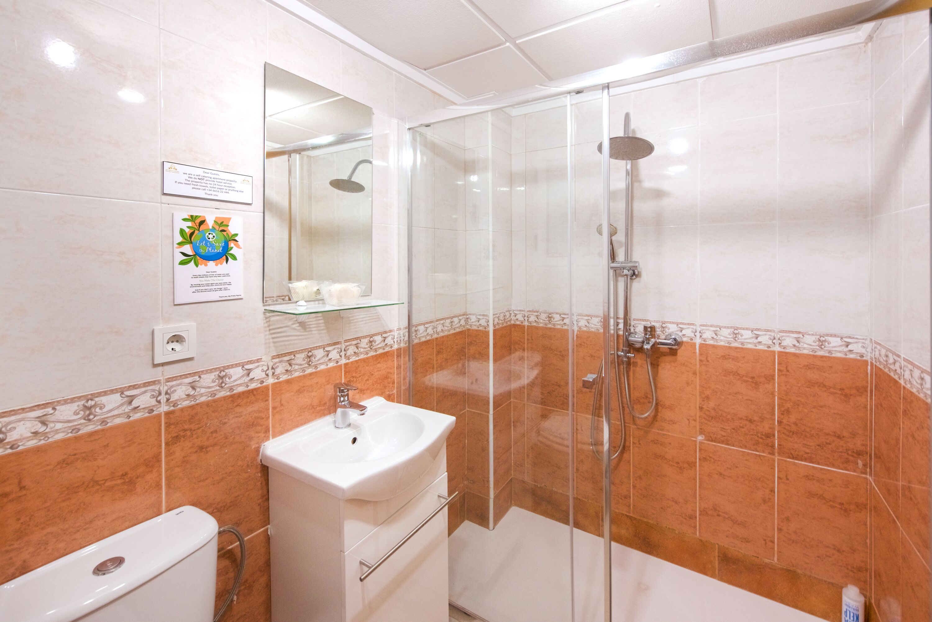 Un baño moderno con ducha acristalada, lavabo blanco y retrete.