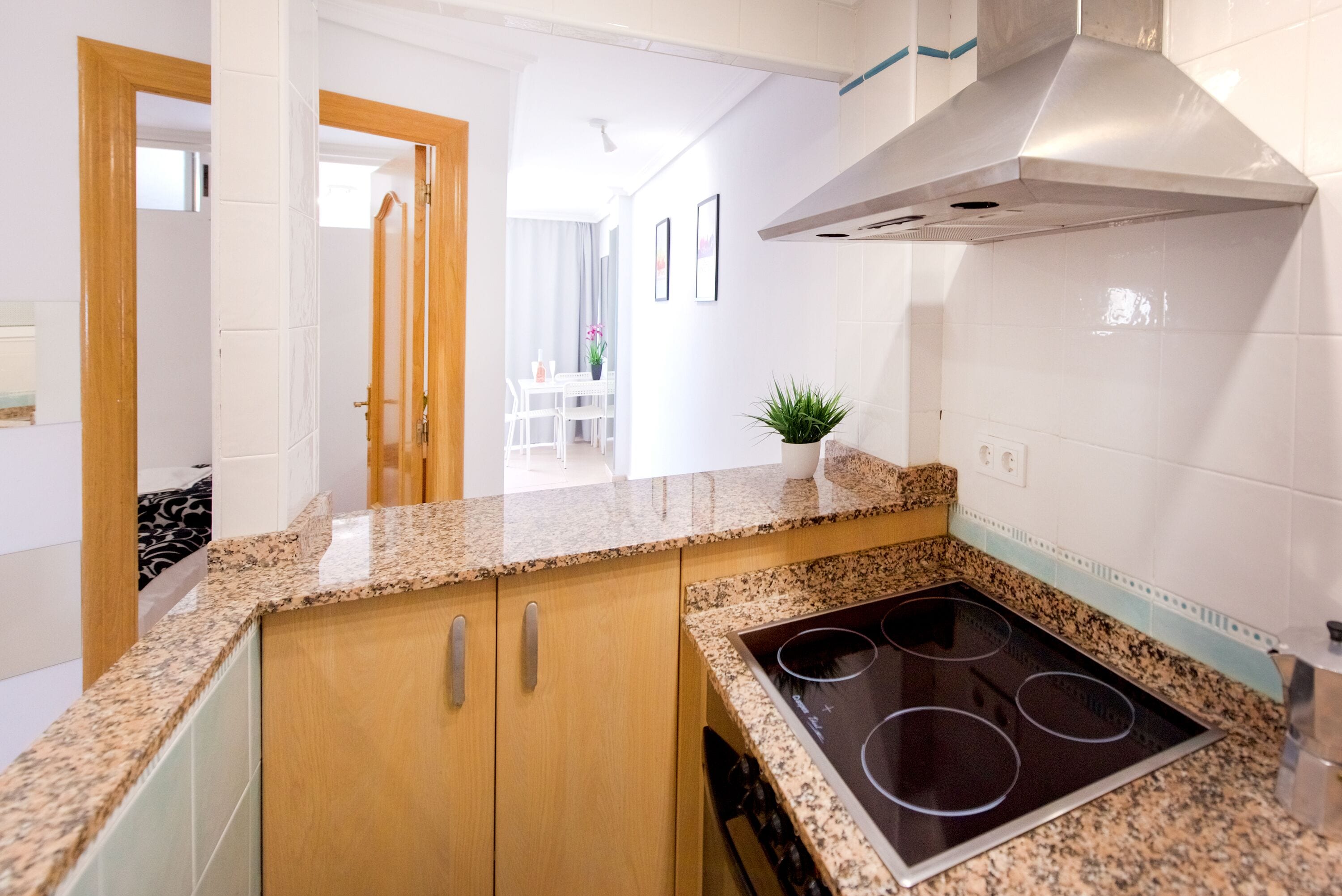 A modern kitchen with granite countertops, a stainless steel range hood, and a built-in stovetop.