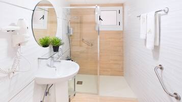 Une salle de bain moderne avec une douche à parois de verre, un lavabo blanc, un miroir et une plante en pot.