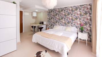 A bedroom with a bed, a desk, a chair, a wardrobe, and a bathroom visible in the background.