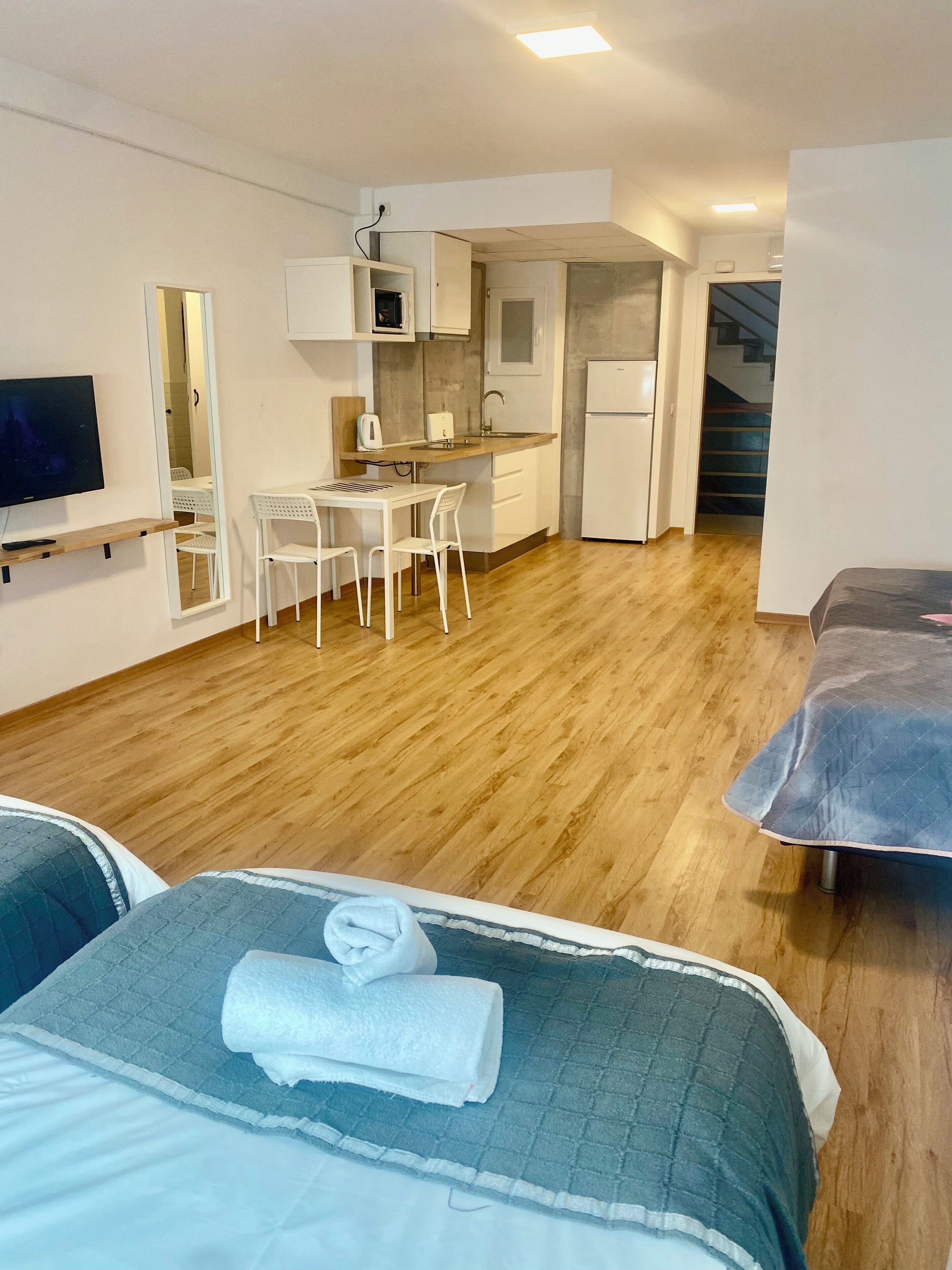 A compact room with a bed, a small kitchenette, a dining area, and a TV.
