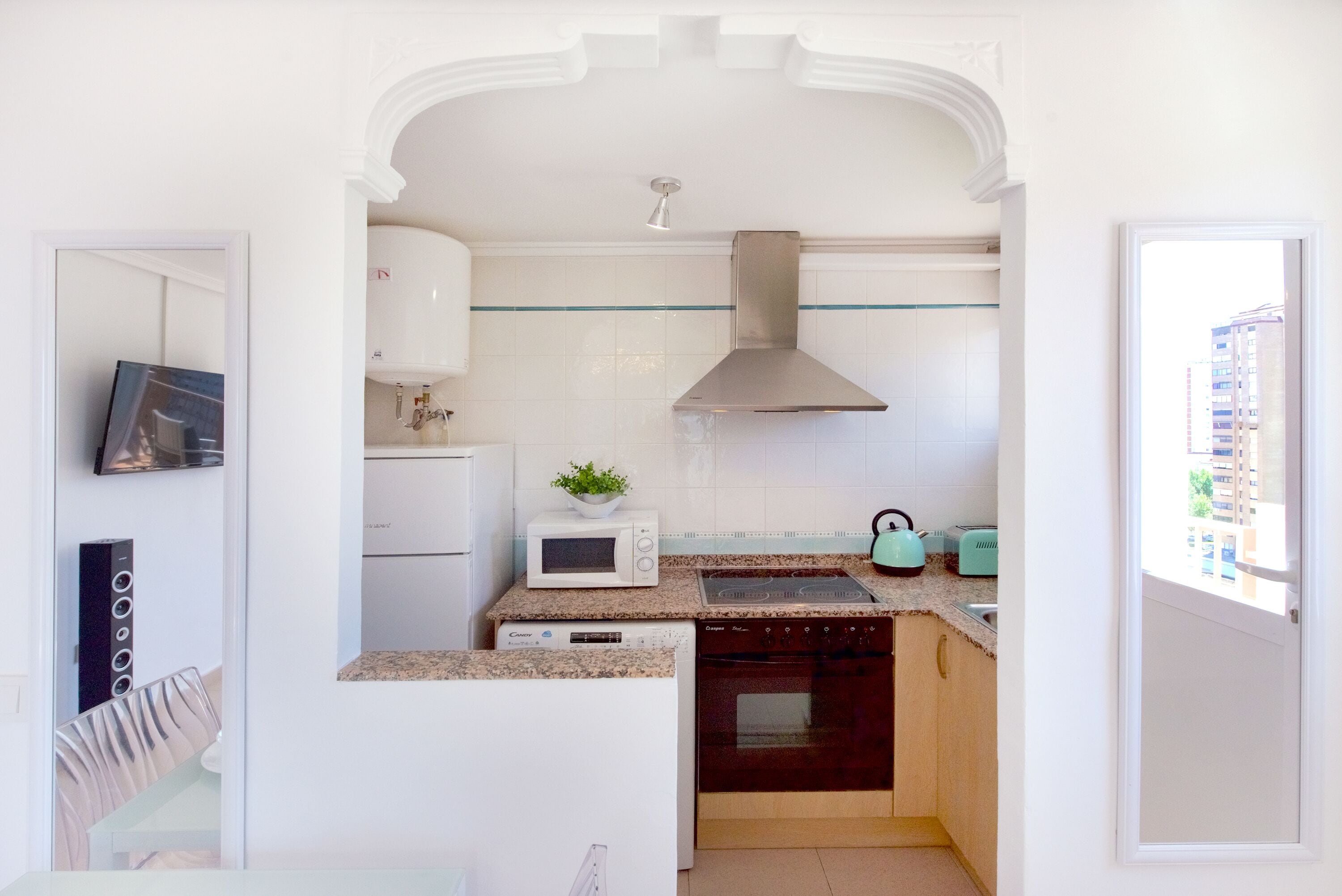 A compact kitchen with white cabinetry, a microwave, a toaster, and a dishwasher.