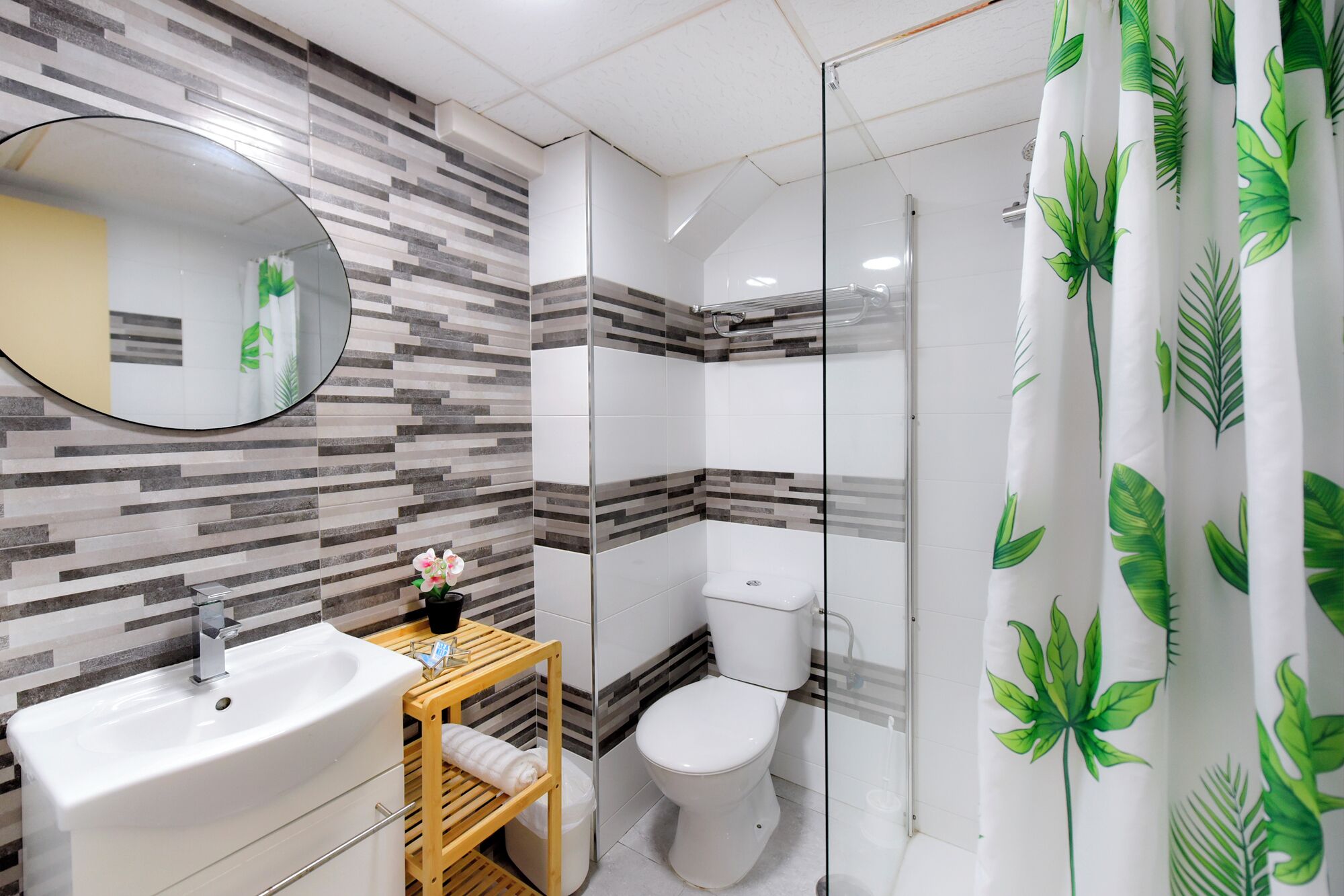 A bathroom with a modern design, featuring a sink, toilet, and shower area.