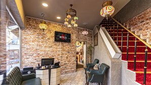 Una habitación acogedora con pared de ladrillo, letrero de Netflix, escalera con alfombra roja y suelo estampado.