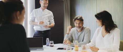A meeting room with a table, laptops, and documents.