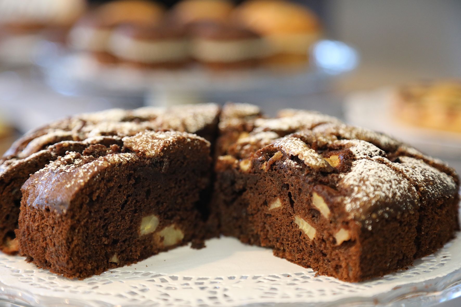 Un pastel con nueces visibles y una capa de azúcar glas sobre un plato blanco.