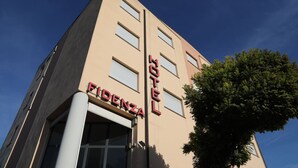 A hotel building with a beige facade, a prominent 'FIDENZA HOTEL' sign, and a tree in the foreground. - Fidenza Hotel (Fidenza)