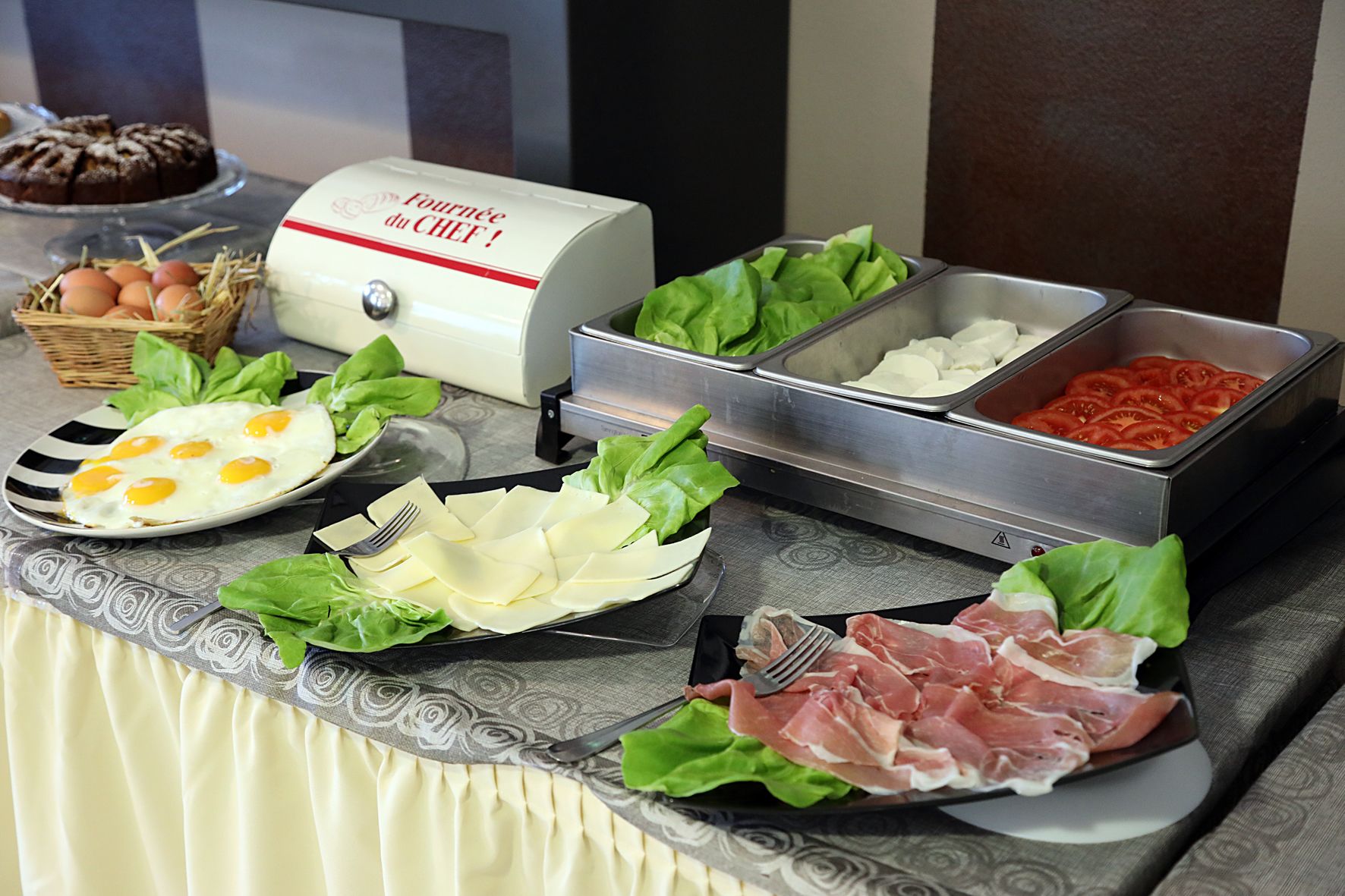 En buffet med forskellige retter, herunder æg, ost, salat, tomater og kød.