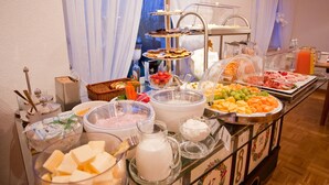 Un bufé con diversos alimentos y bebidas, entre ellos frutas, quesos y una jarra de leche.