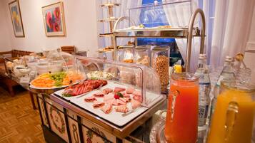 A buffet with various food items and beverages, including a glass of orange juice and a pitcher of orange juice.