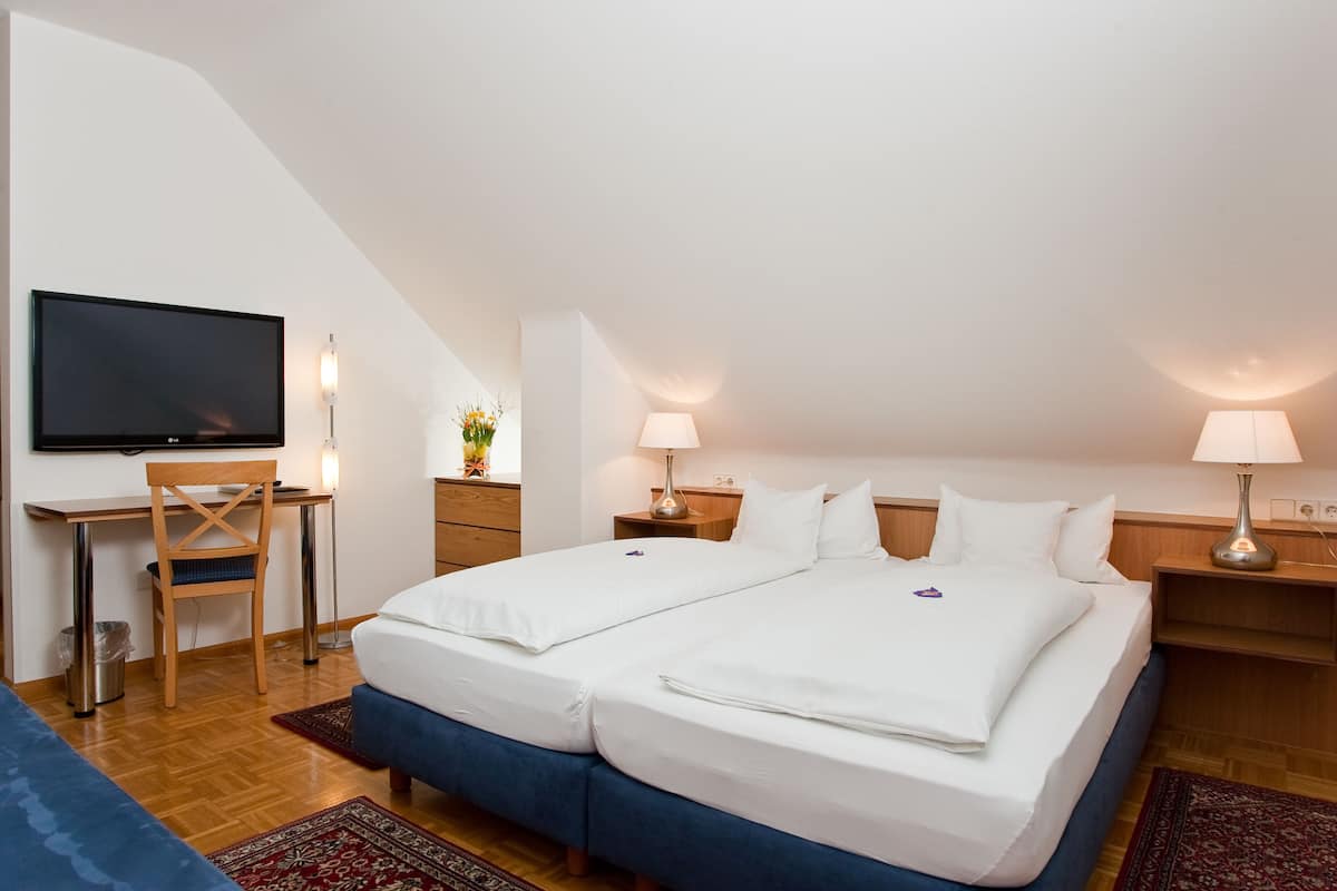 Habitación de hotel con una cama grande, un escritorio, un televisor y dos lámparas de noche.