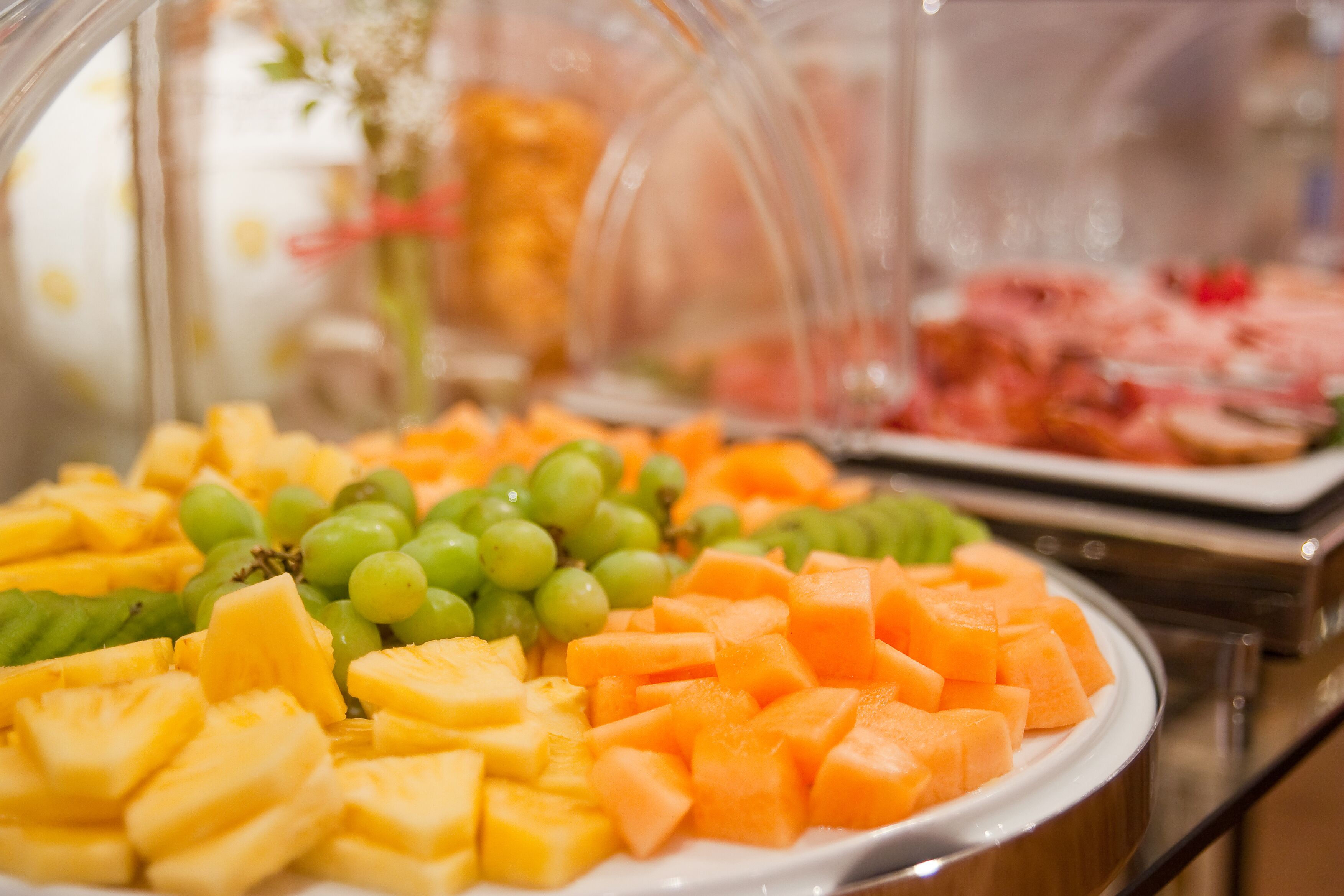 Un bufé con diversas frutas y una vitrina en el fondo.