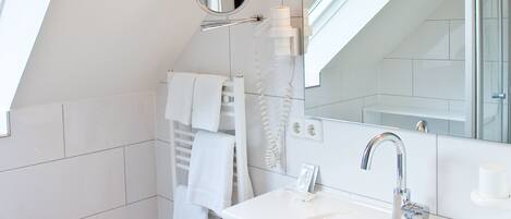 A modern bathroom with a skylight, a large mirror, a sink, and a towel rack.