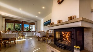 A cozy room with a fireplace, dining area, and large windows.