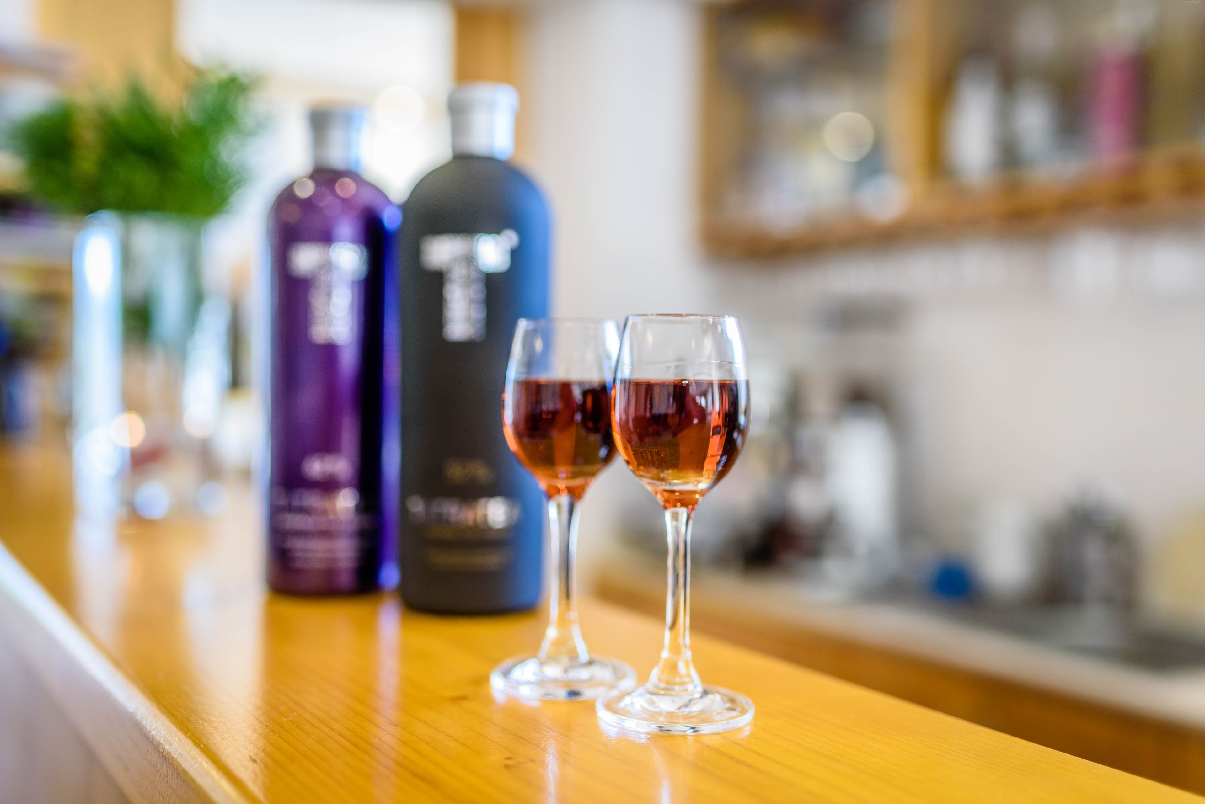 Una barra con dos copas de vino tinto y dos botellas de licor.