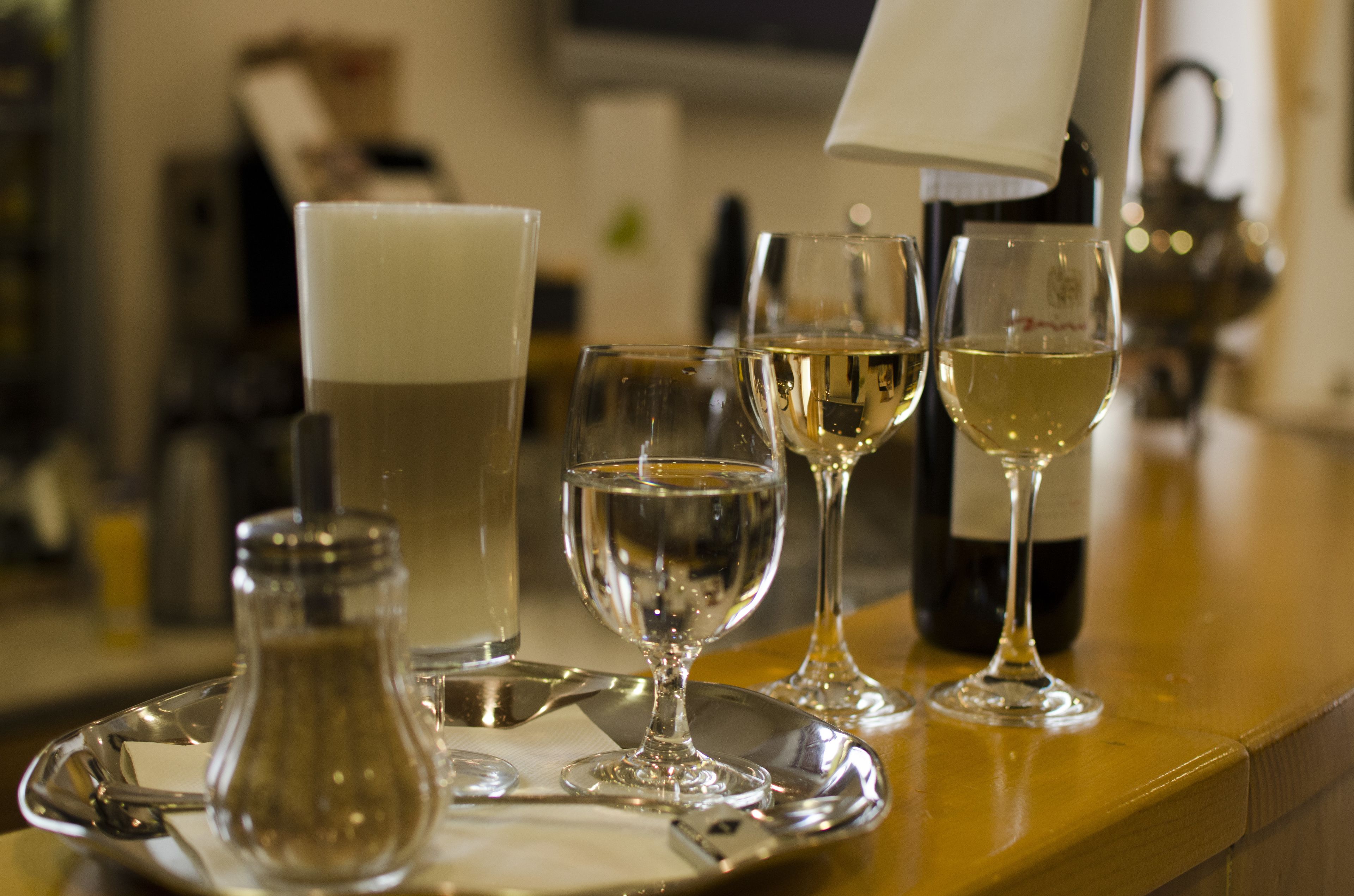 Un ambiente da bar con calici di vino e una bottiglia su un vassoio.