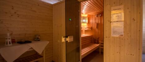Un sauna de madera con un banco, una mesa con una toalla y una puerta de cristal.