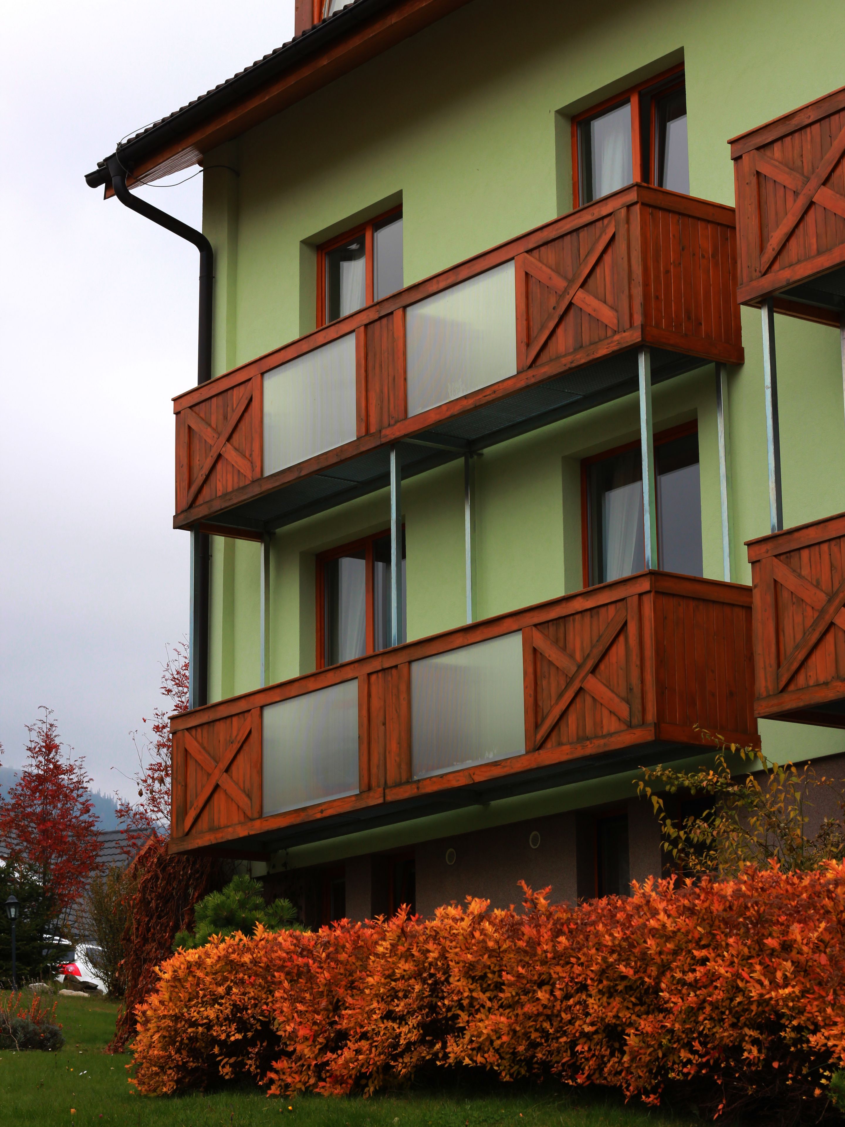 A multi-story building with balconies and a green facade.
