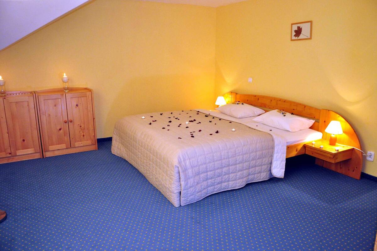 Een slaapkamer met een bed, twee bedlampen, een houten garderobe en één decoratie aan de muur.