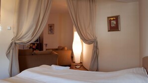 Una habitación de hotel con cama, sofá, lámpara y cortinas.