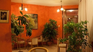 Una habitación con paredes anaranjadas, sillas de madera y plantas en macetas.