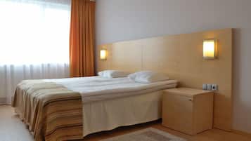 Una habitación de hotel moderna con una cama grande, un cabecero de madera, lámparas de noche y un pequeño mueble de madera.