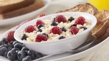 A bowl of cereal with berries and toast on a plate.