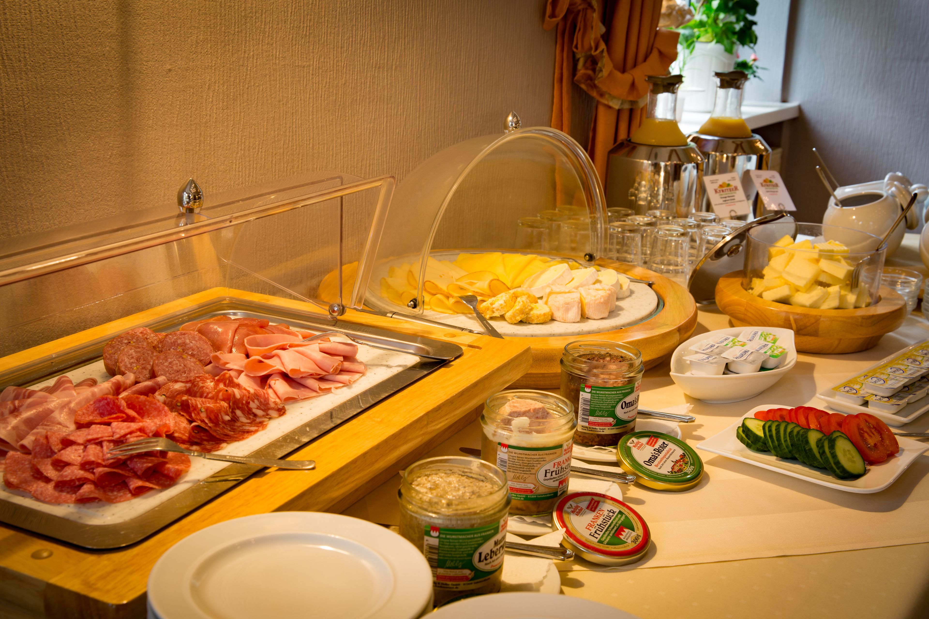 A buffet with various food items including meats, cheeses, and fruits.