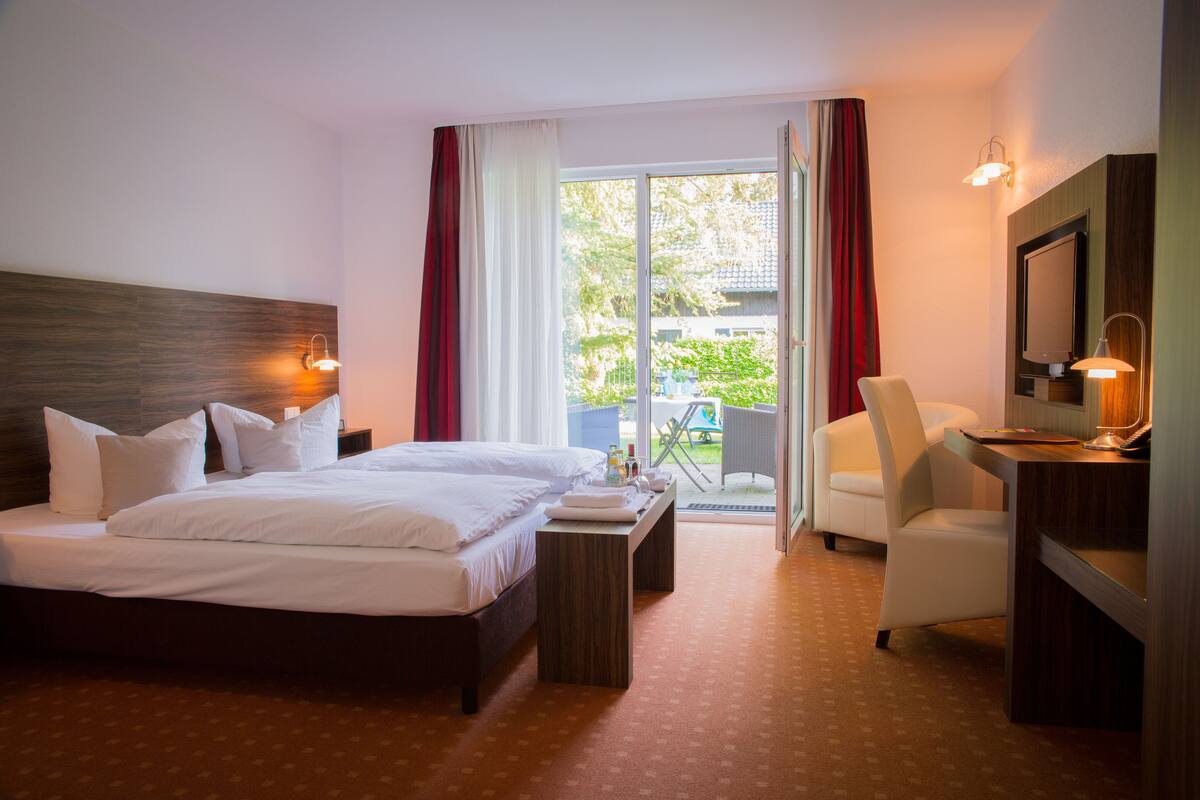 A hotel room with a bed, a desk, a chair, and a TV.