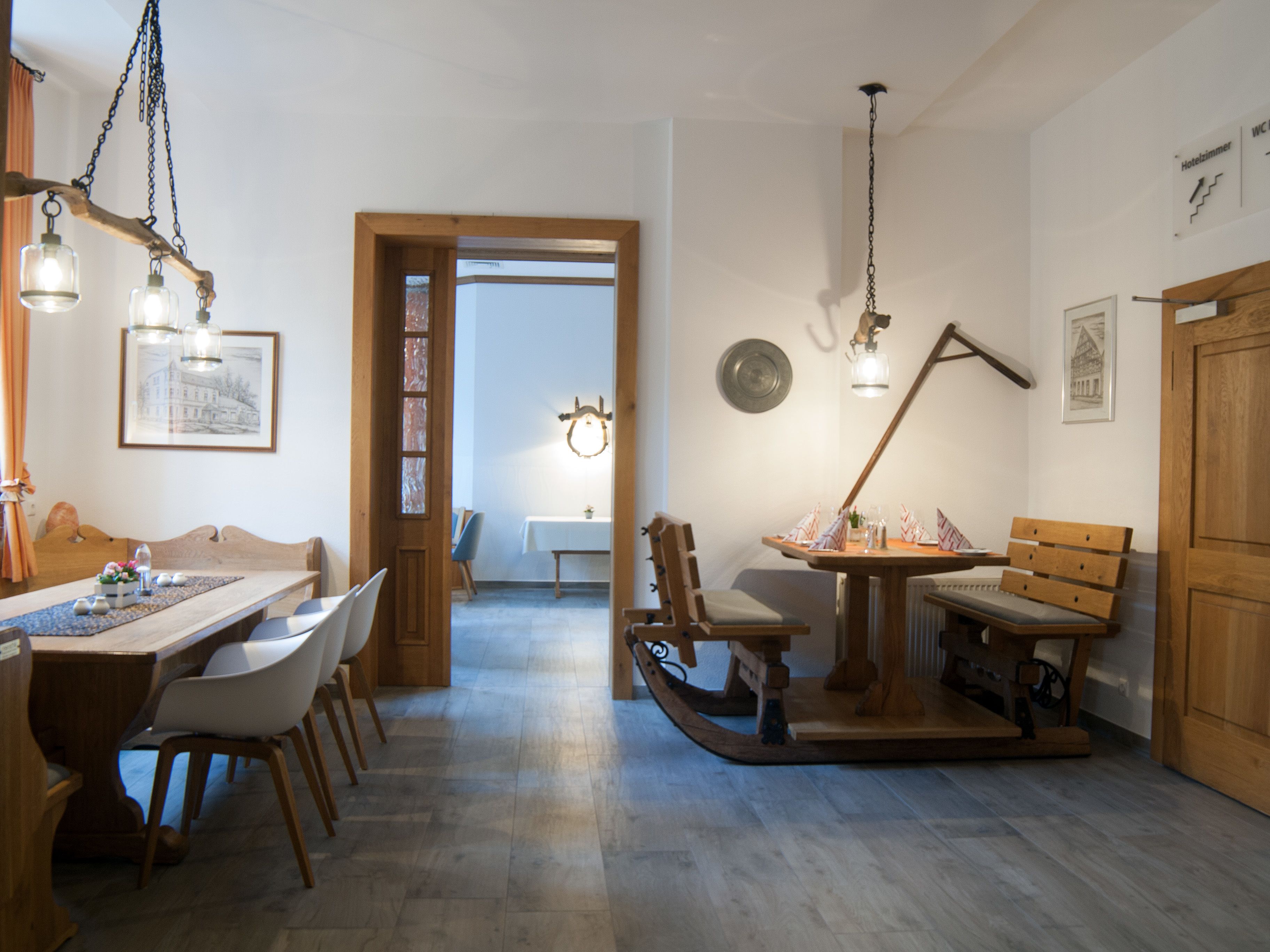 Un'area pranzo con un tavolo e sedie in legno, una panca di legno e un lampadario.